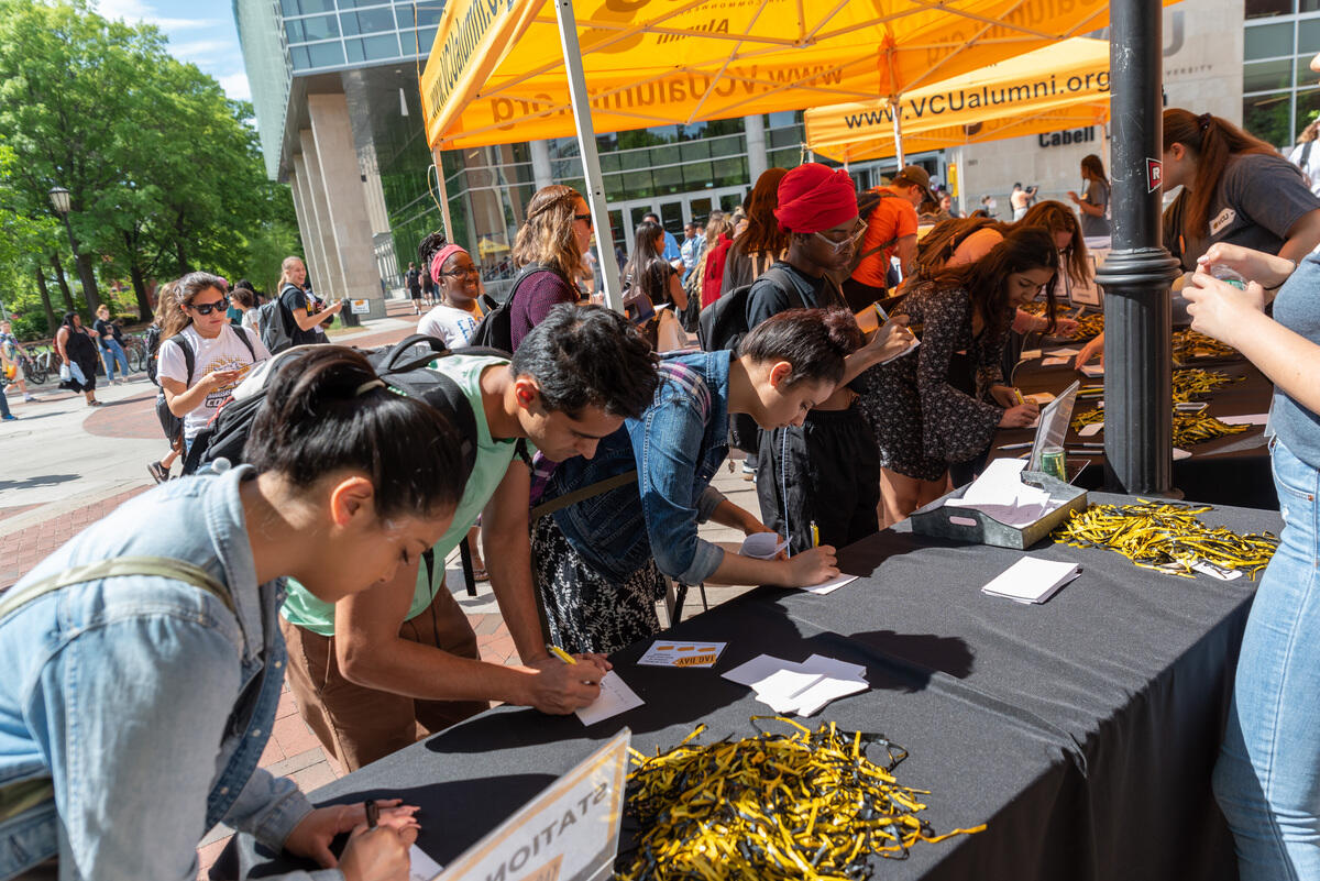 Students leaning over a table filling out pieces of paper. 