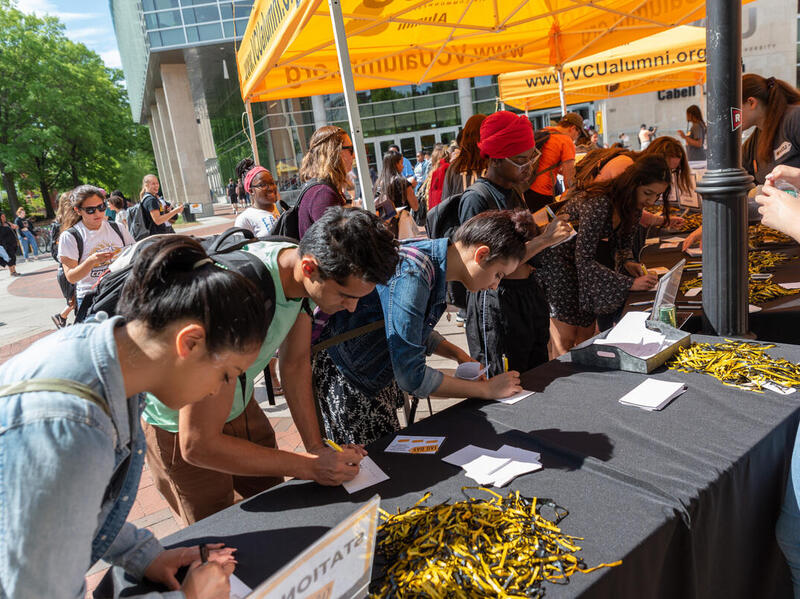 Students leaning over a table filling out pieces of paper. 