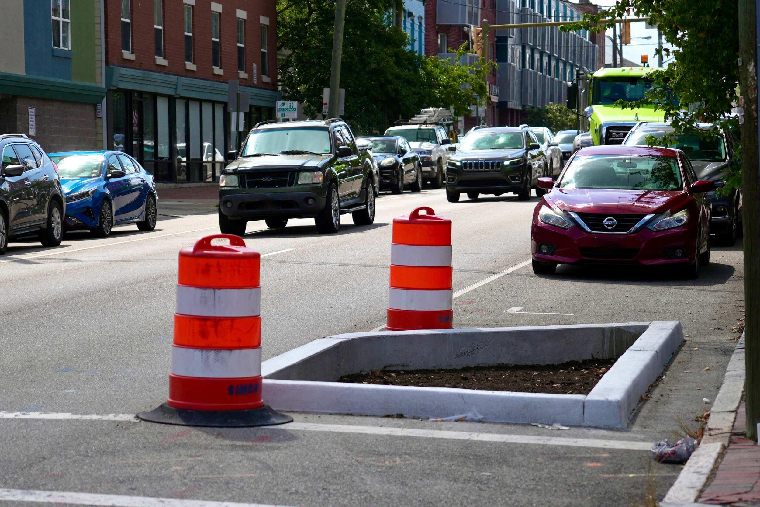 A photo of a curb with two traffic drums on either side of it. 