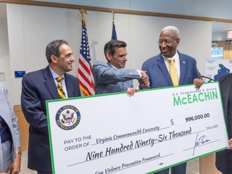 U.S. Rep. A. Donald McEachin hands a ceremonial check to VCU President Michael Rao, Ph.D., and Michel Aboutanos, M.D., the medical director of VCU Medical Center’s Level I Trauma Center and Trauma System Network and the director of the VCU Injury and Violence Prevention Program, for the RVA Gun Violence Prevention Framework. 