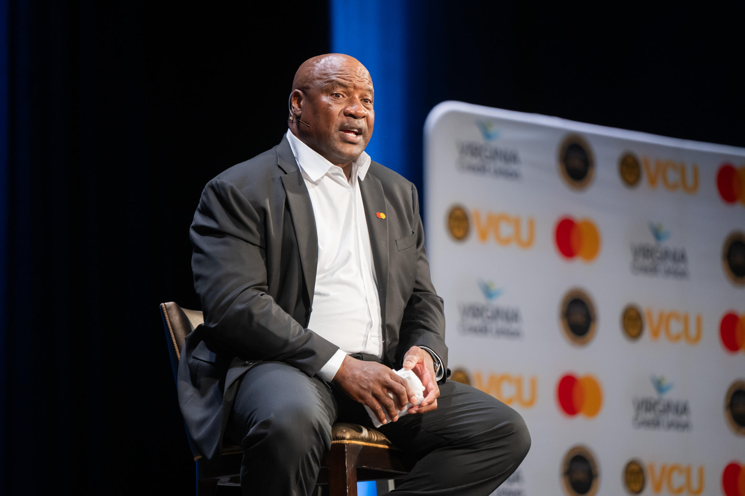 Bo Jackson, wearing a suit, sits on a chair on a stage and speaks.