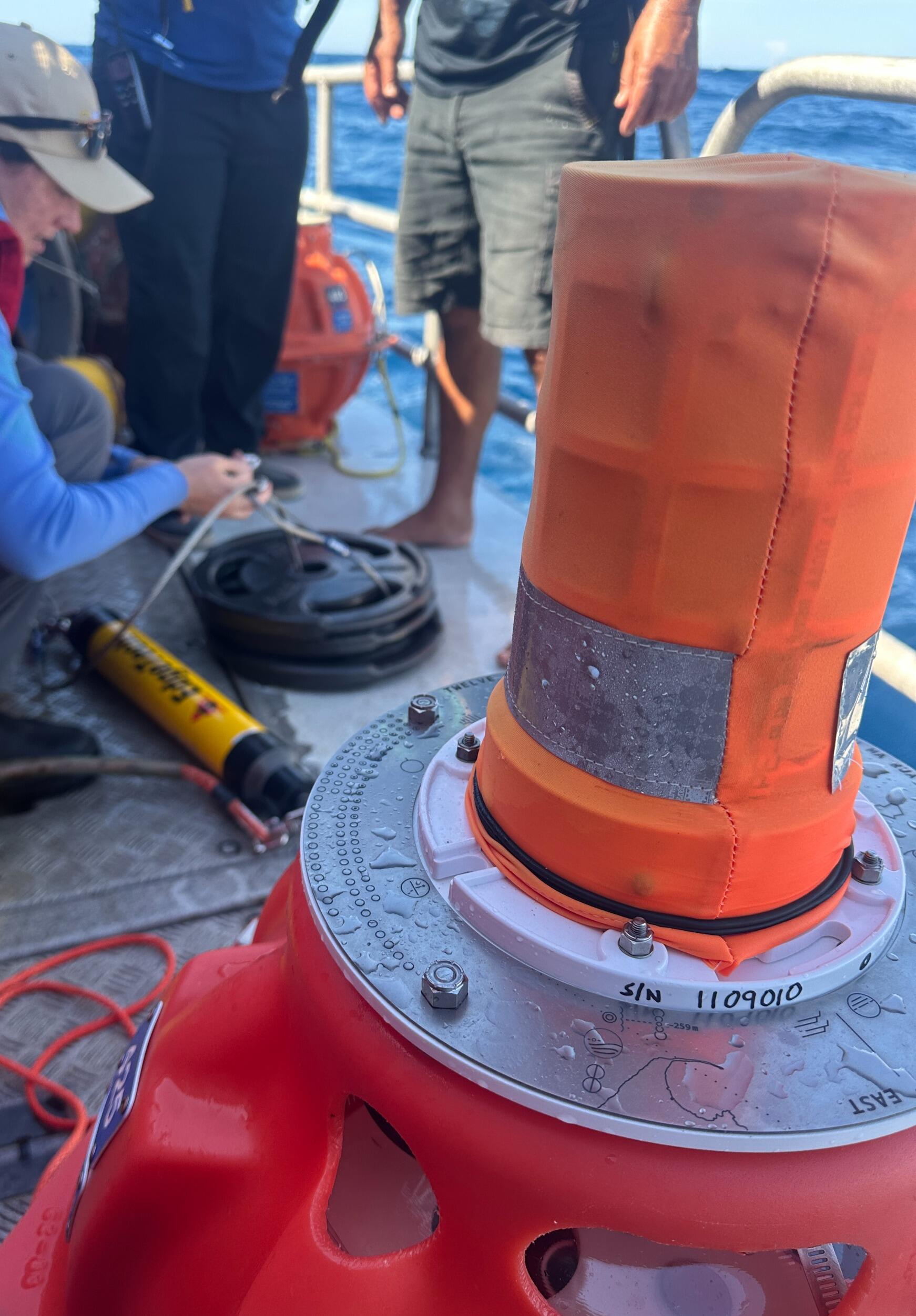 A photo of a metal wheel on a yellow and red object sitting on a boat. 