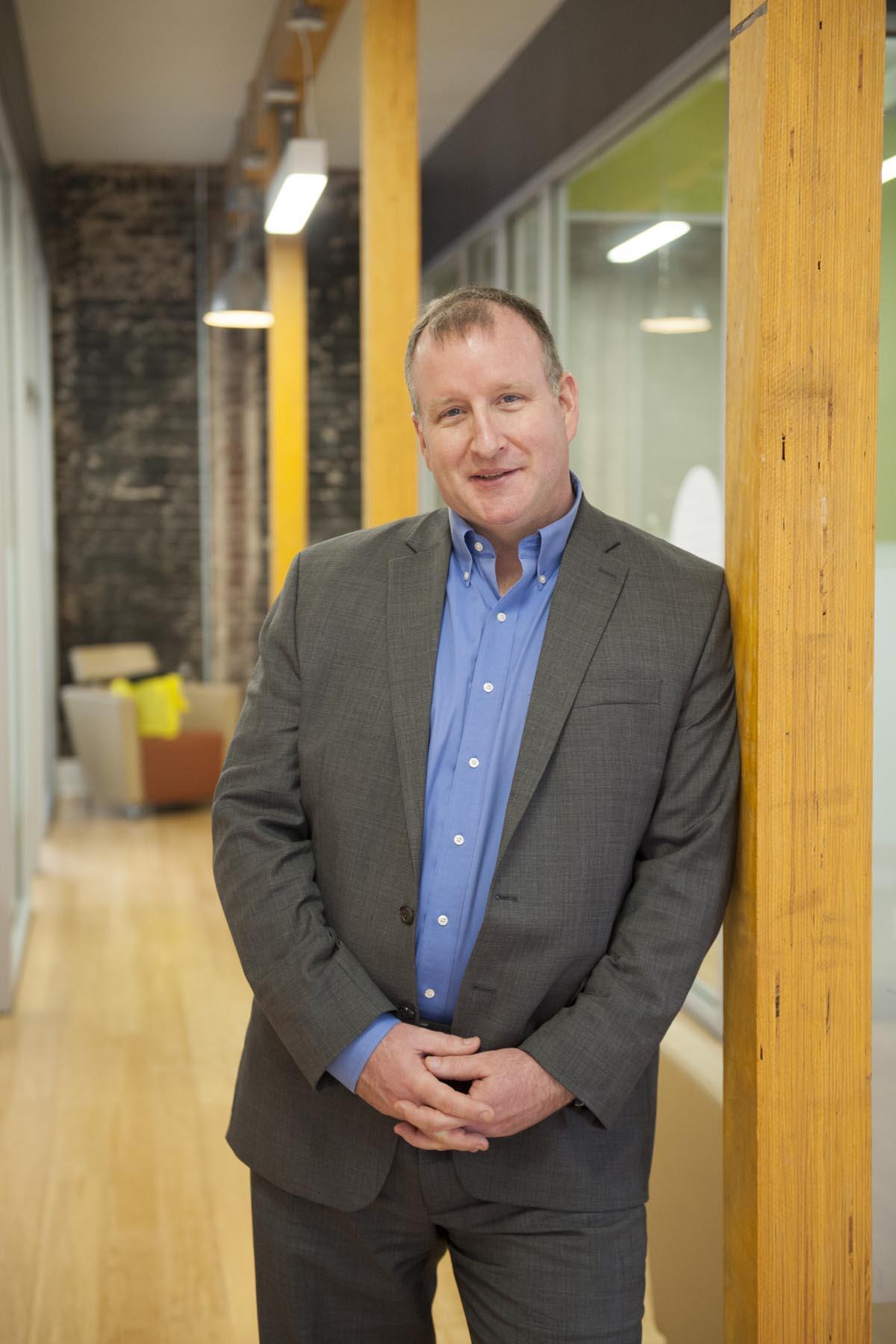 Picture of Jason RW Merrick, standing and leaning on a wall.