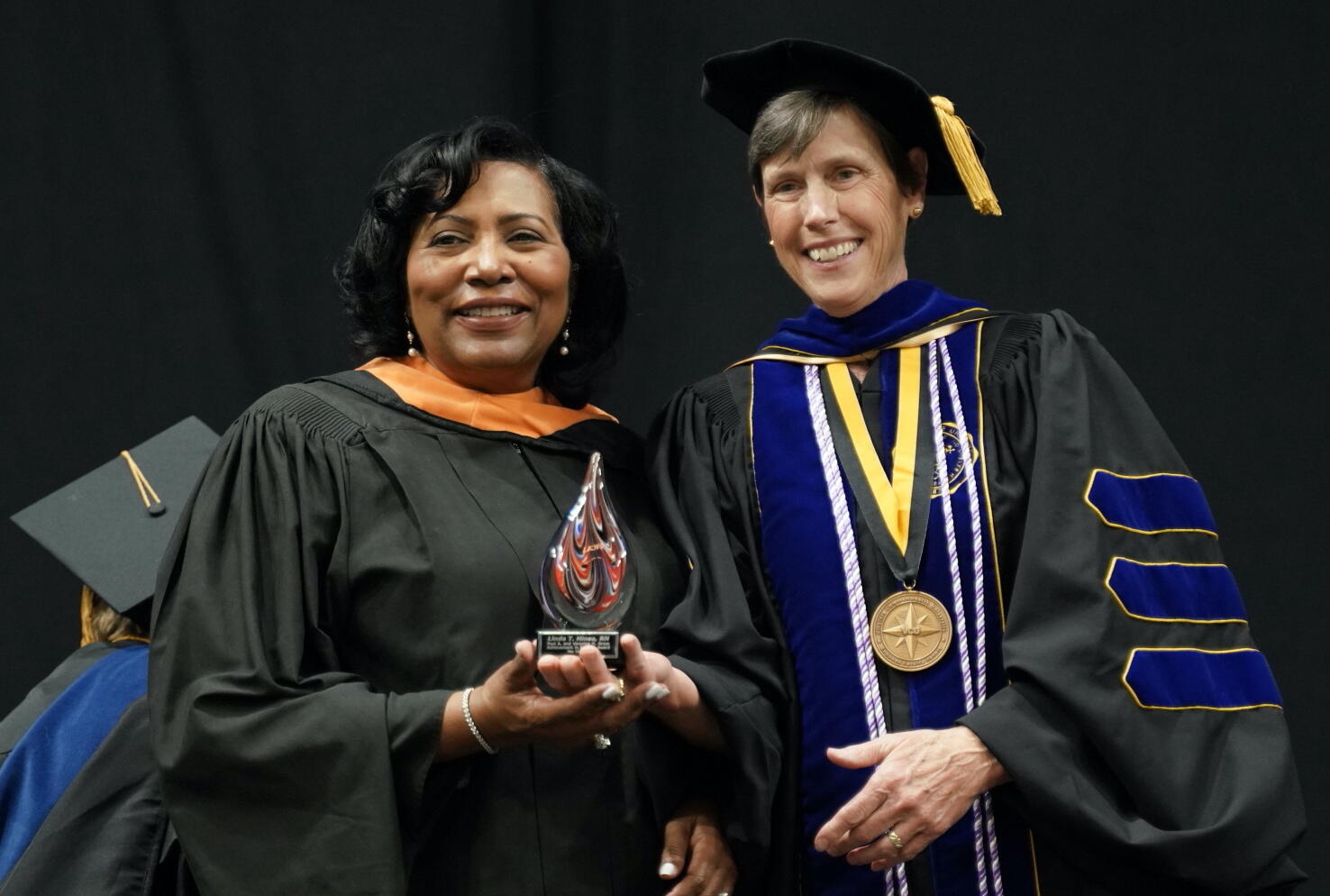 Linda Hines (left) receives the the Paul A. and Veronica H. Gross Achievement in Nursing Award from Jean Giddens, Ph.D., dean and professor at VCU School of Nursing, during the School of Nursing's commencement ceremony.