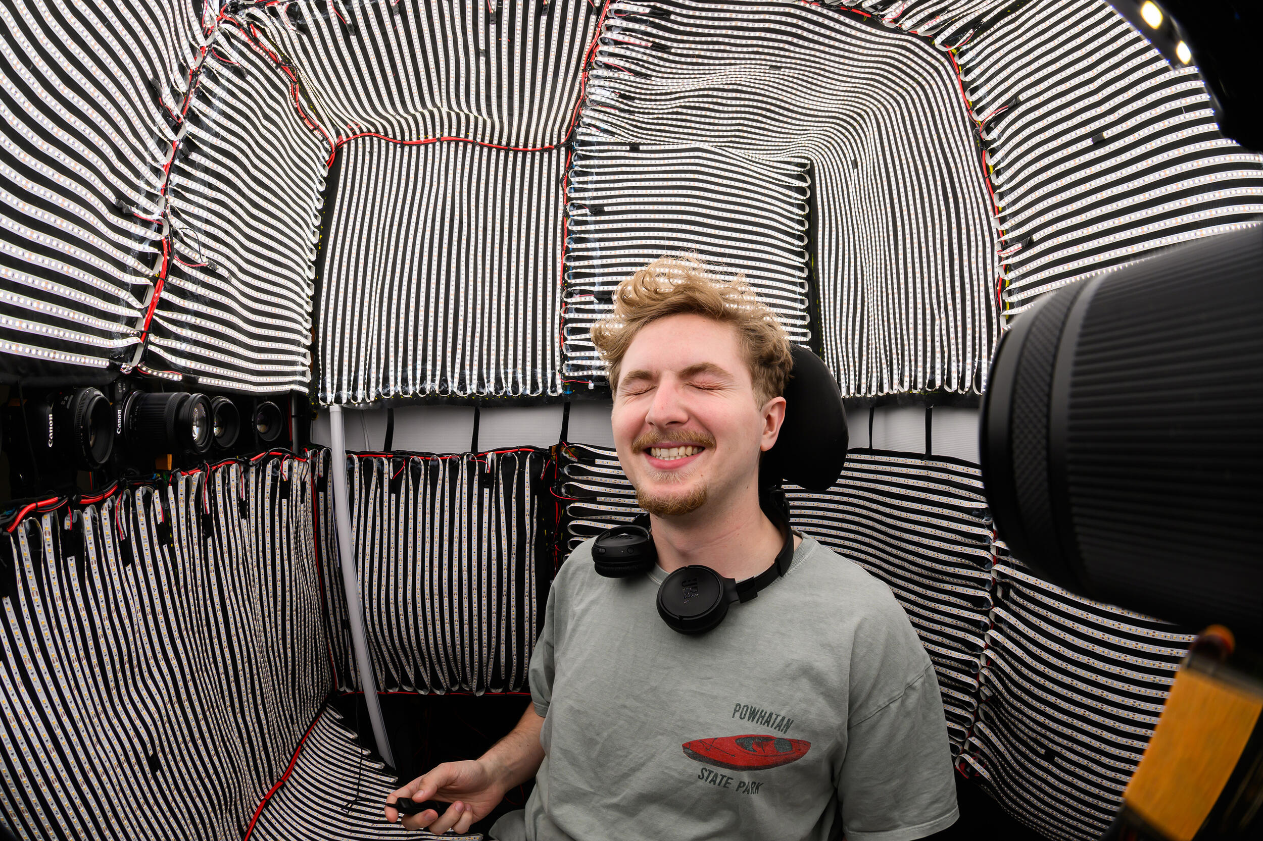 A photo of a man sitting in a room covered in lights. 