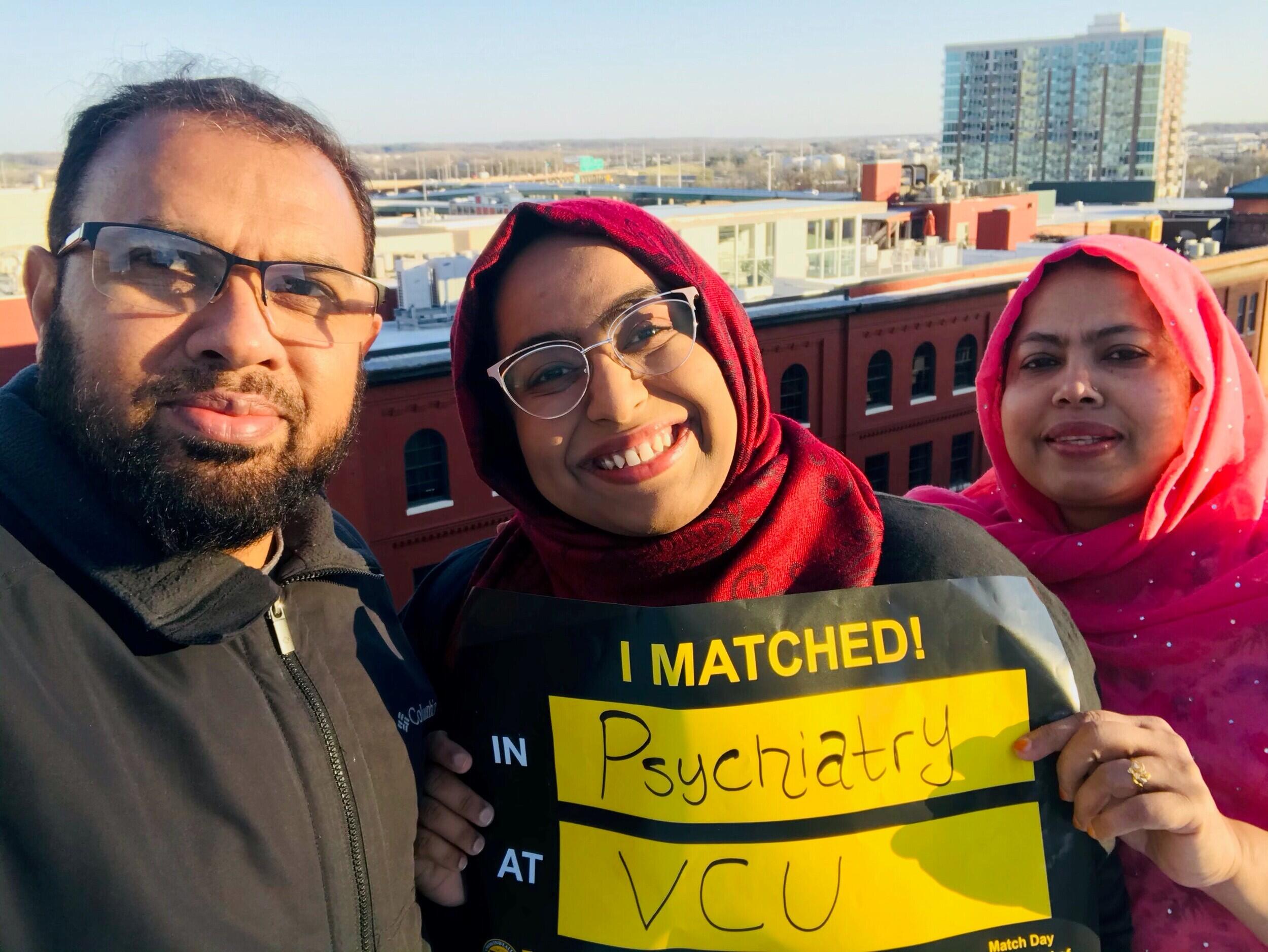 Shahida Mizan holding a match day sign with two people.