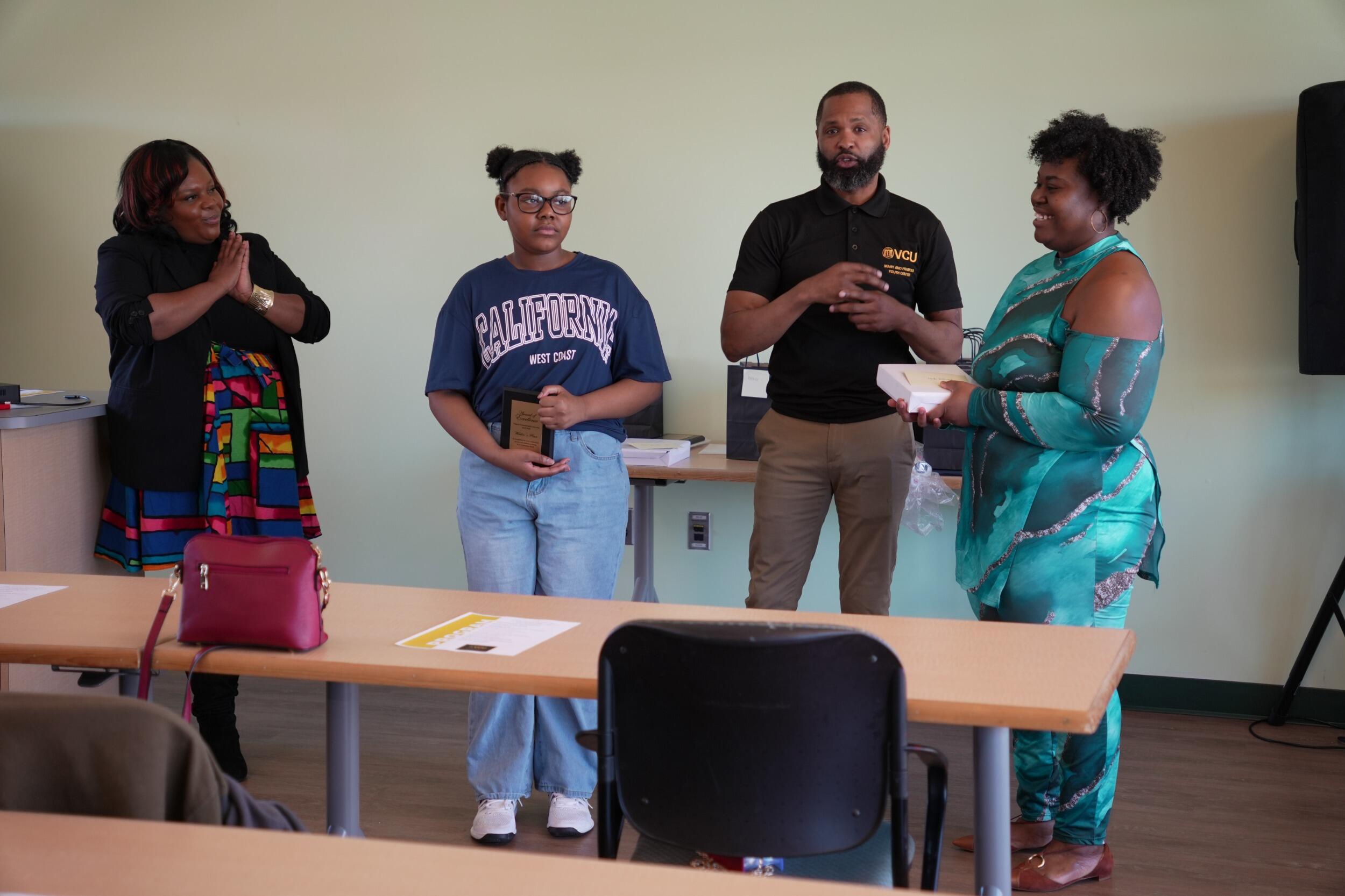 A photo of four people standing in the back of a room. 