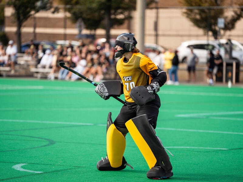 A photo of a field hockey player standing on a field. 