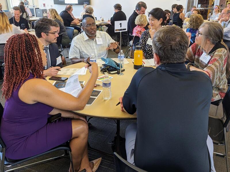 A photo of six people sitting at a circular table. 