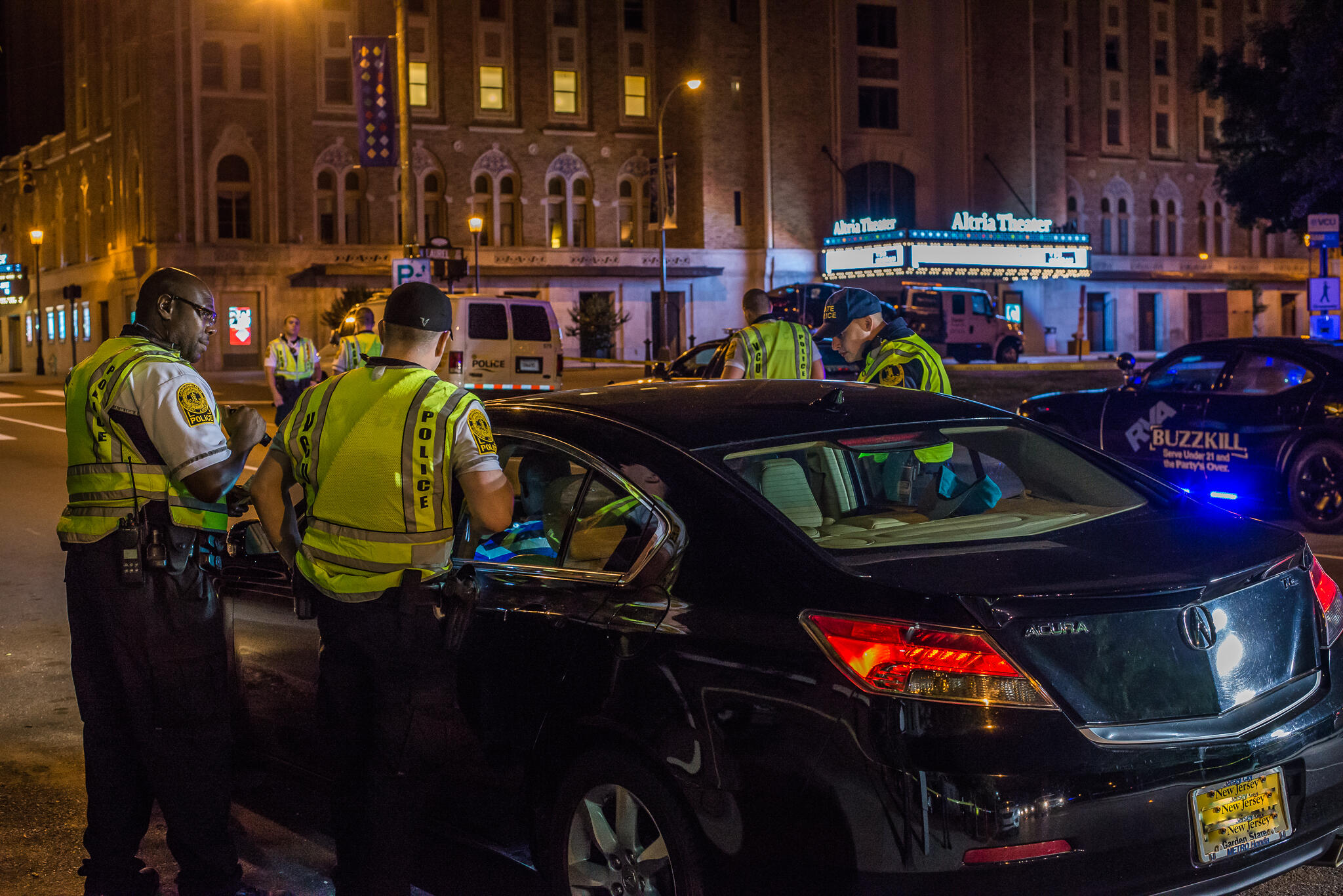 A photo of three police officers standing around a black car. 
