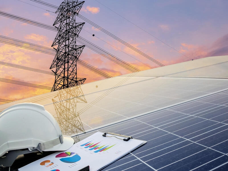 A photo of a helmet and clip board on top of a solar panel. In the background 