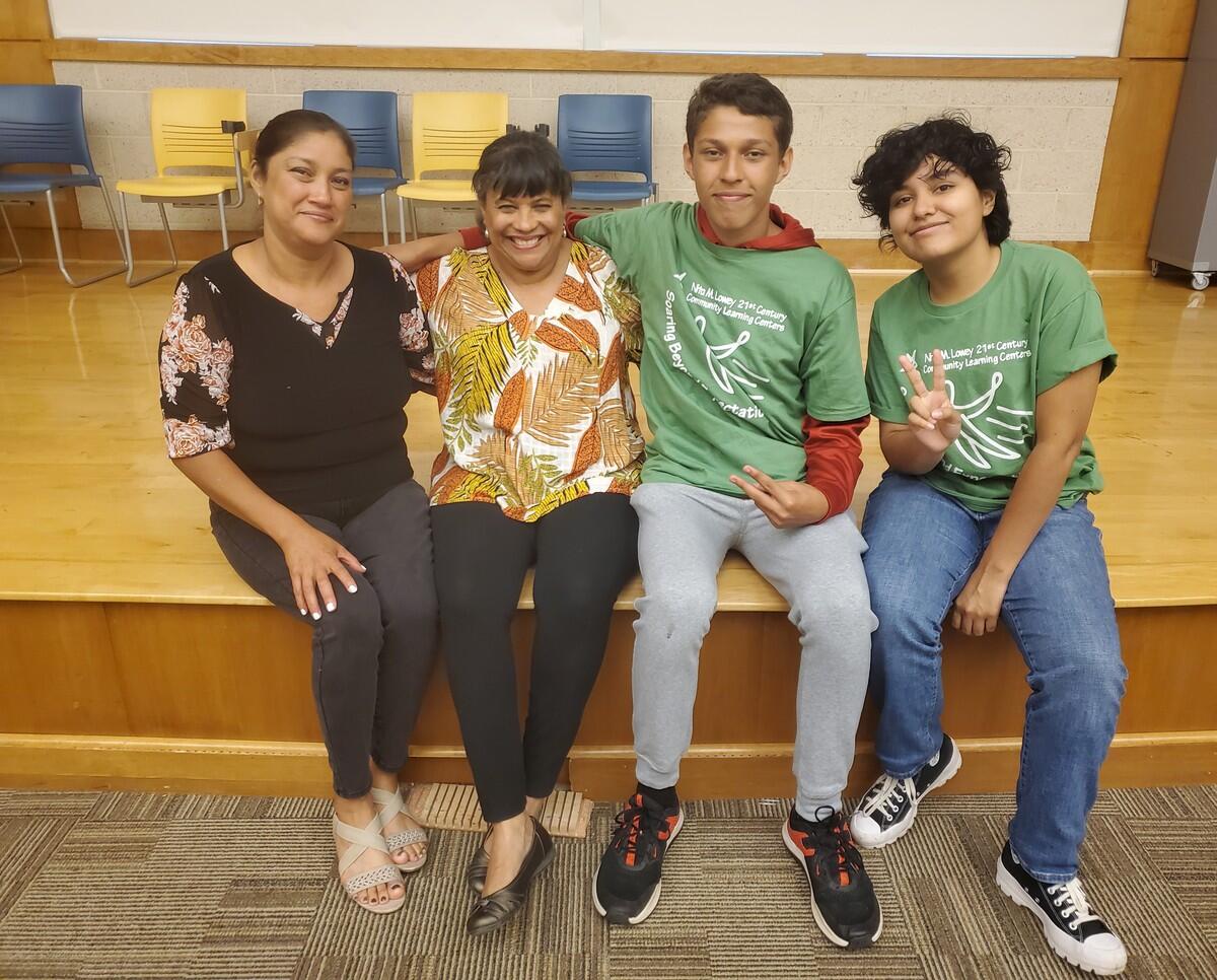 A photo of four people sitting on the edge of a stage 
