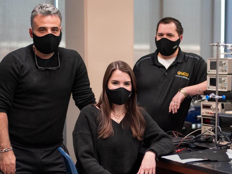 Three people in a laboratory wearing facial masks.