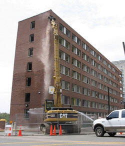 Beginning of the End. A demolition team, for Skanska USA Building, Inc., uses an excavation tool equipped with a grappling attachment to take the “first bite” out of Randolph-Minor Hall.