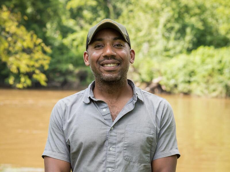 A photo of a man standing outside. 