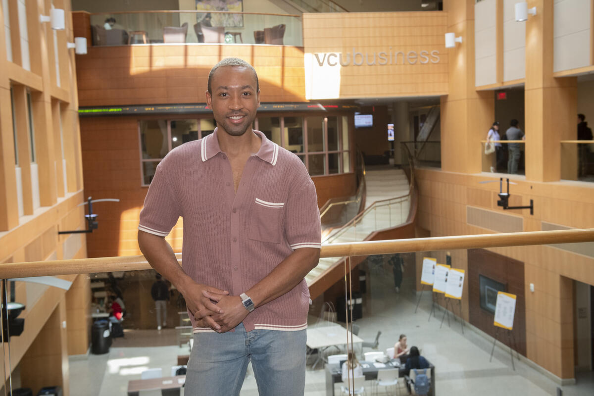 A man wearing a button up short sleeve shirt leaning against a railing. 