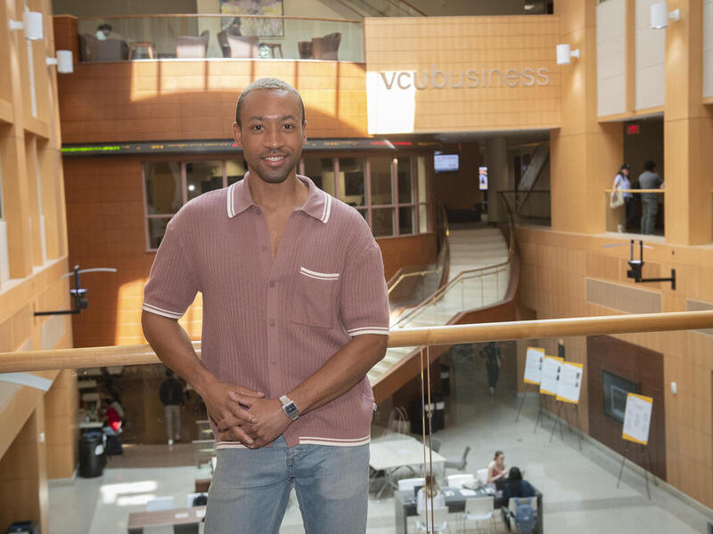A man wearing a button up short sleeve shirt leaning against a railing. 