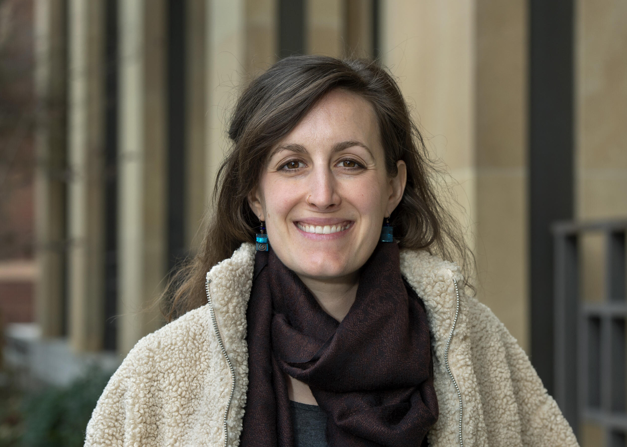 A woman smiling while standing outside of a building. 