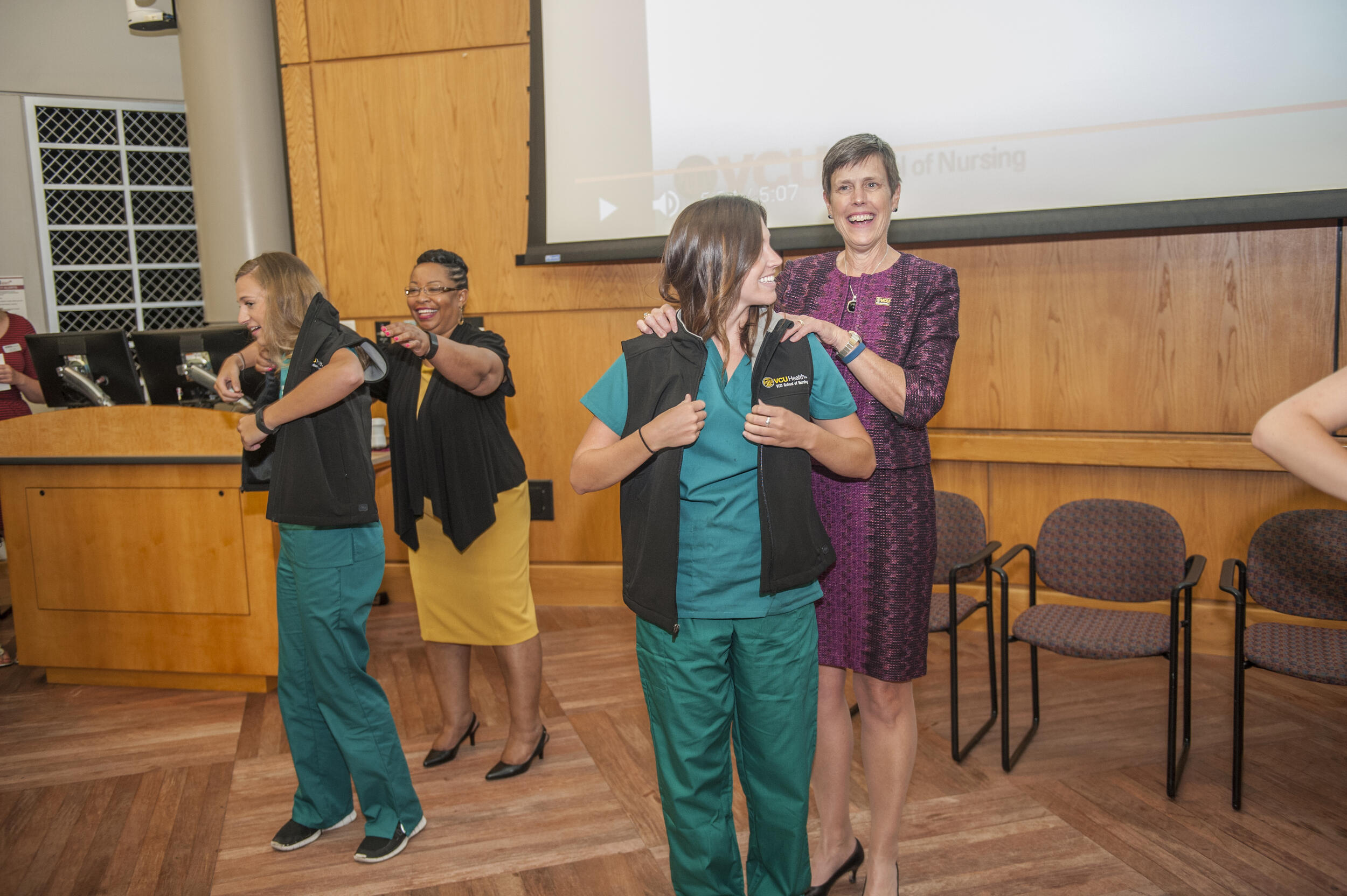 A photo of two women putting on vests on two other women. 