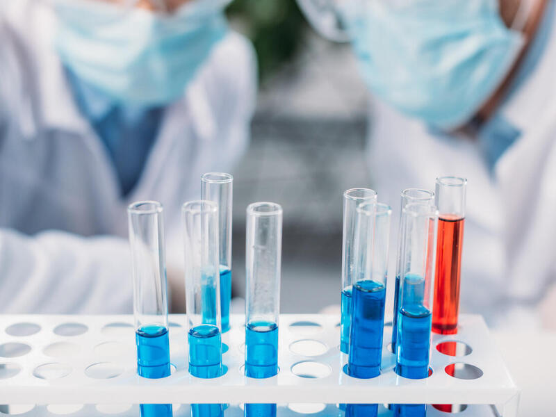 Two persons observe test tubes inside of a laboratory.