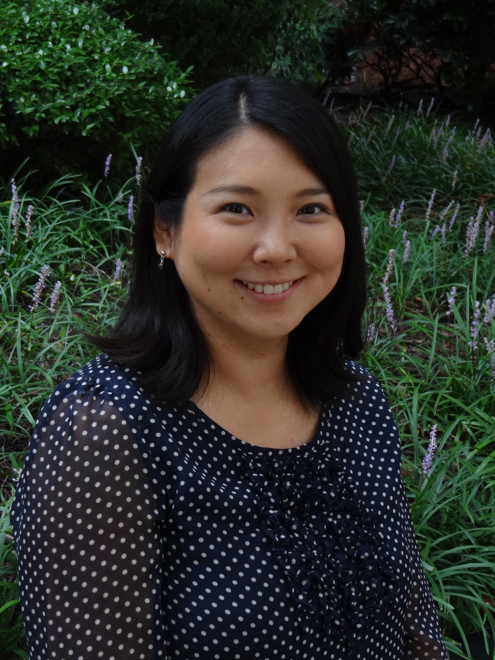 A portrait of a woman with shoulder length black hair wearing a black blouse with white polka dots 