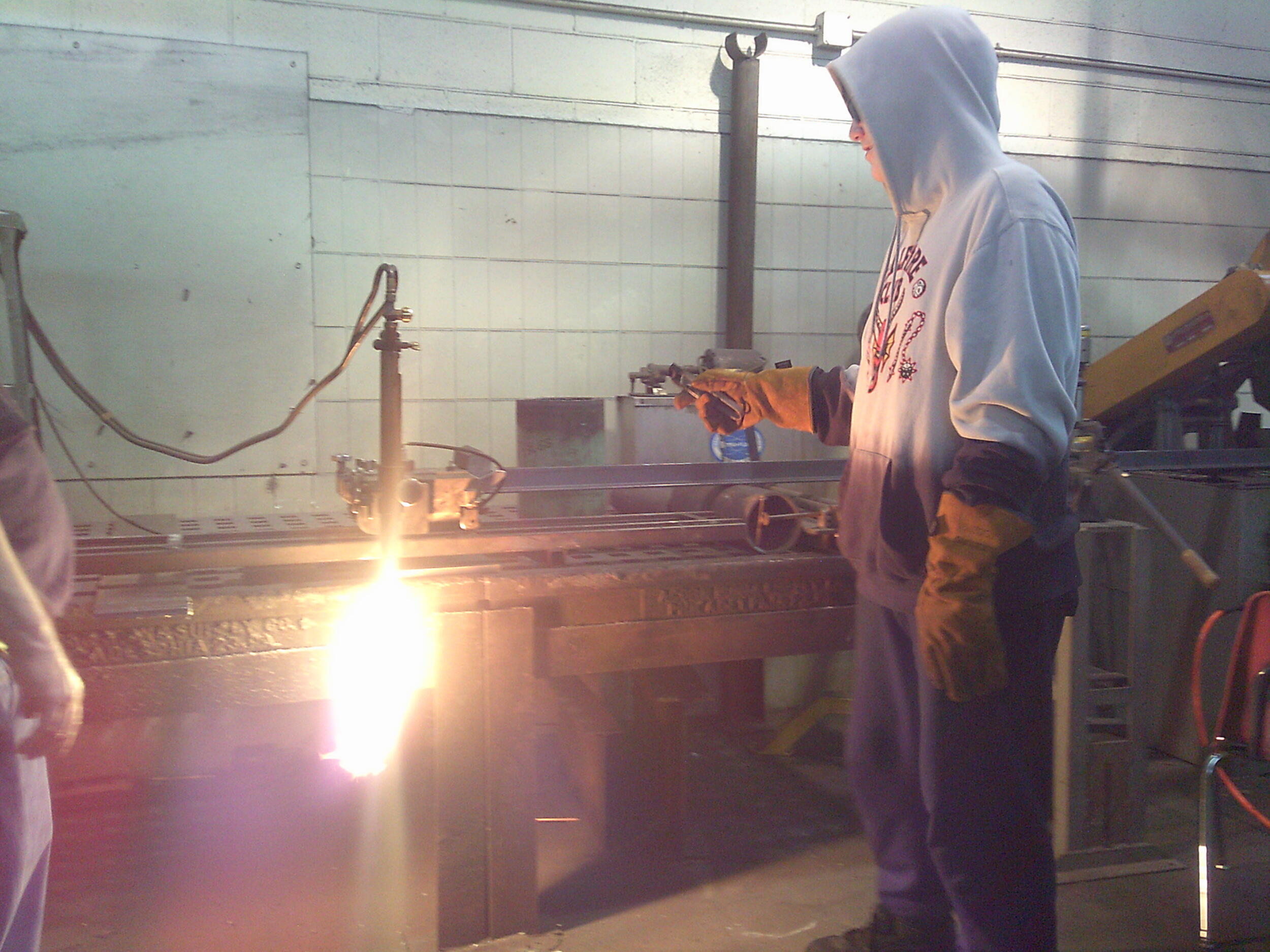 A photo of a man standing in front of a pole with a glowing object attached at the bottom. 