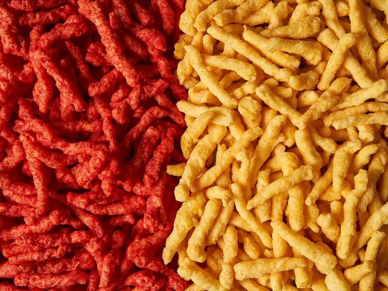 A phorto that shows two piles of Cheetos. On the left are right red colored Cheetos and on the left are light yellow Cheetos. 