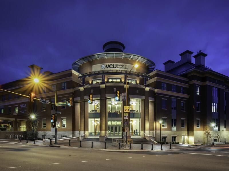 An exterior photo of a VCU College of Engineering building lit up at night.
