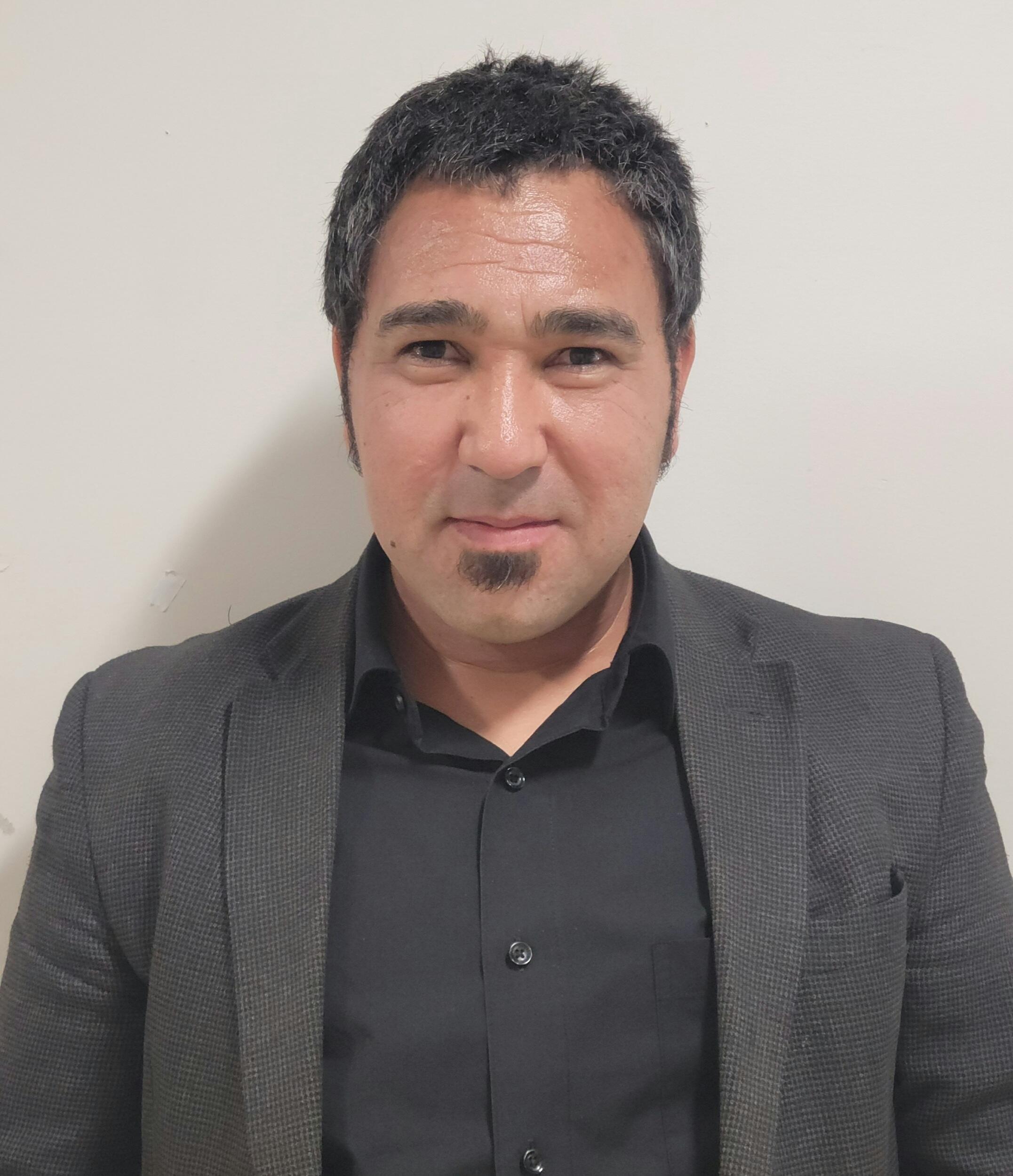 A portait of a man wearing a sportscoat and button up shirt. 