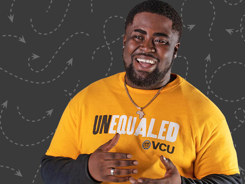 A man smiling at the camera with his arms in front of him and fists against each other 