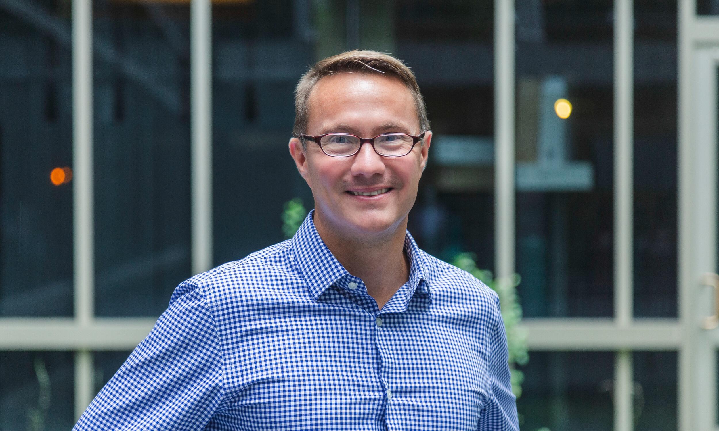 James Ferri, Ph.D., professor and associate chair in VCU’s Department of Chemical and Life Science Engineering, staining in front of some windows and smiling