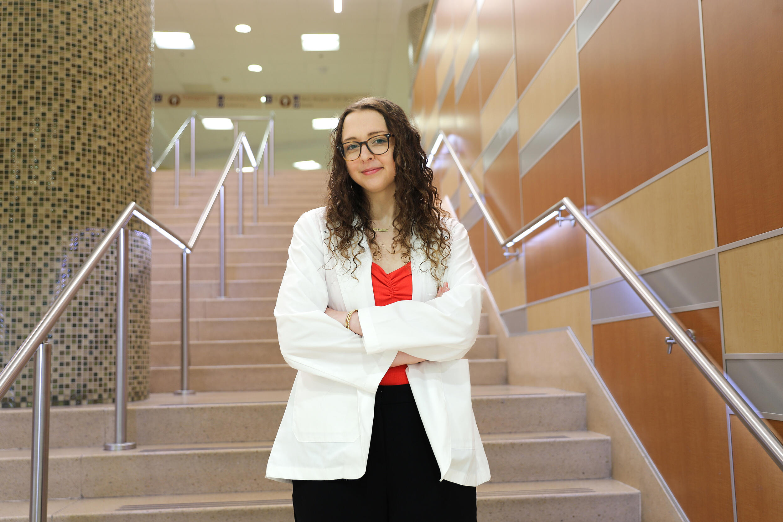 A photo of a woman in a white lab coat standing on a staircase. 