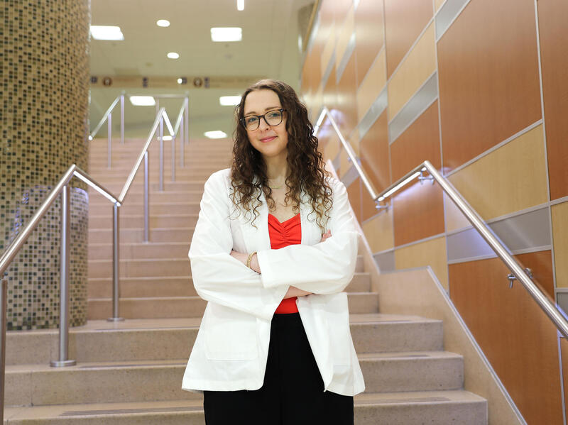 A photo of a woman in a white lab coat standing on a staircase. 