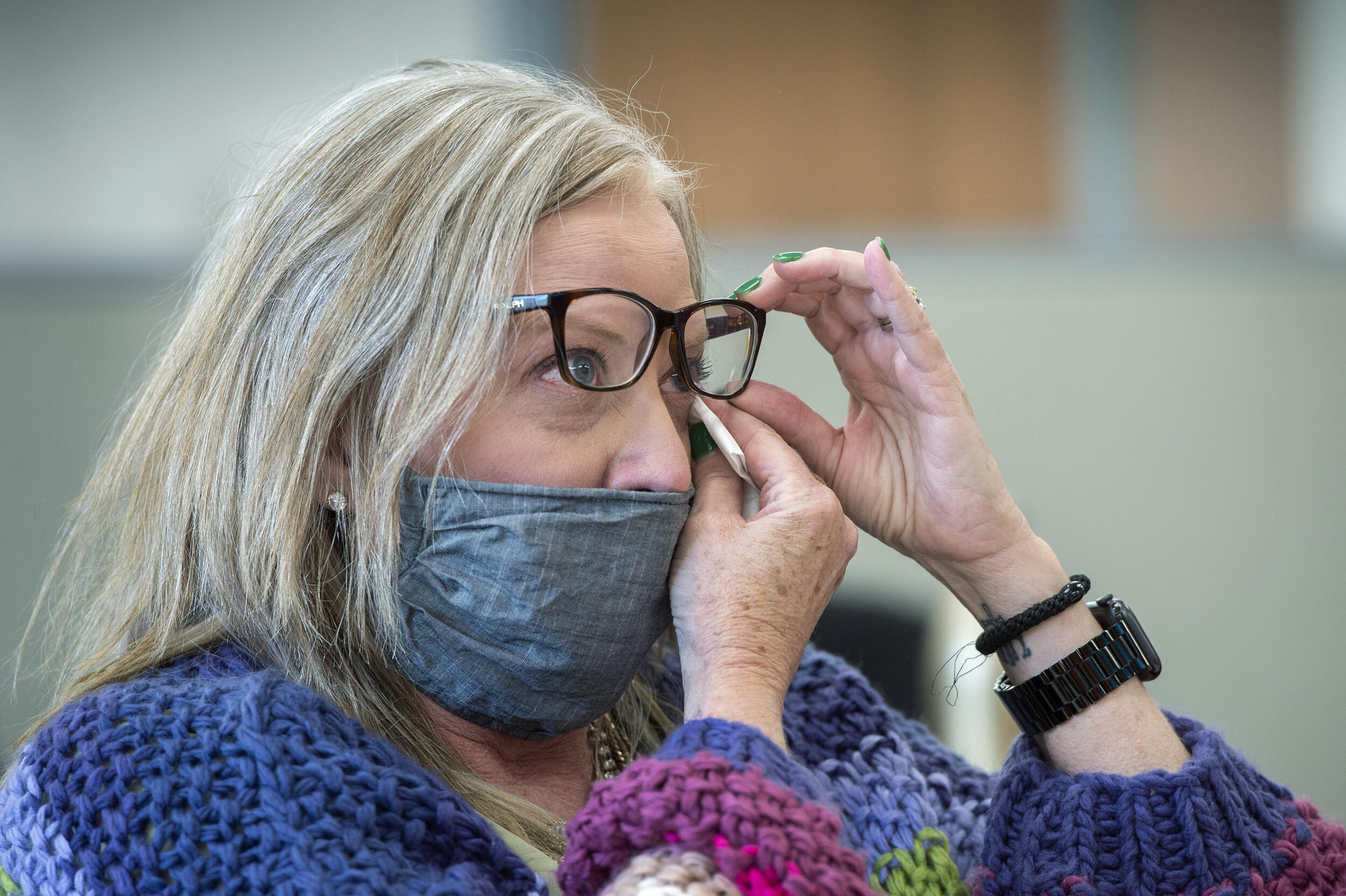 A woman lifting up her glasses to wipe away a tear from her eye