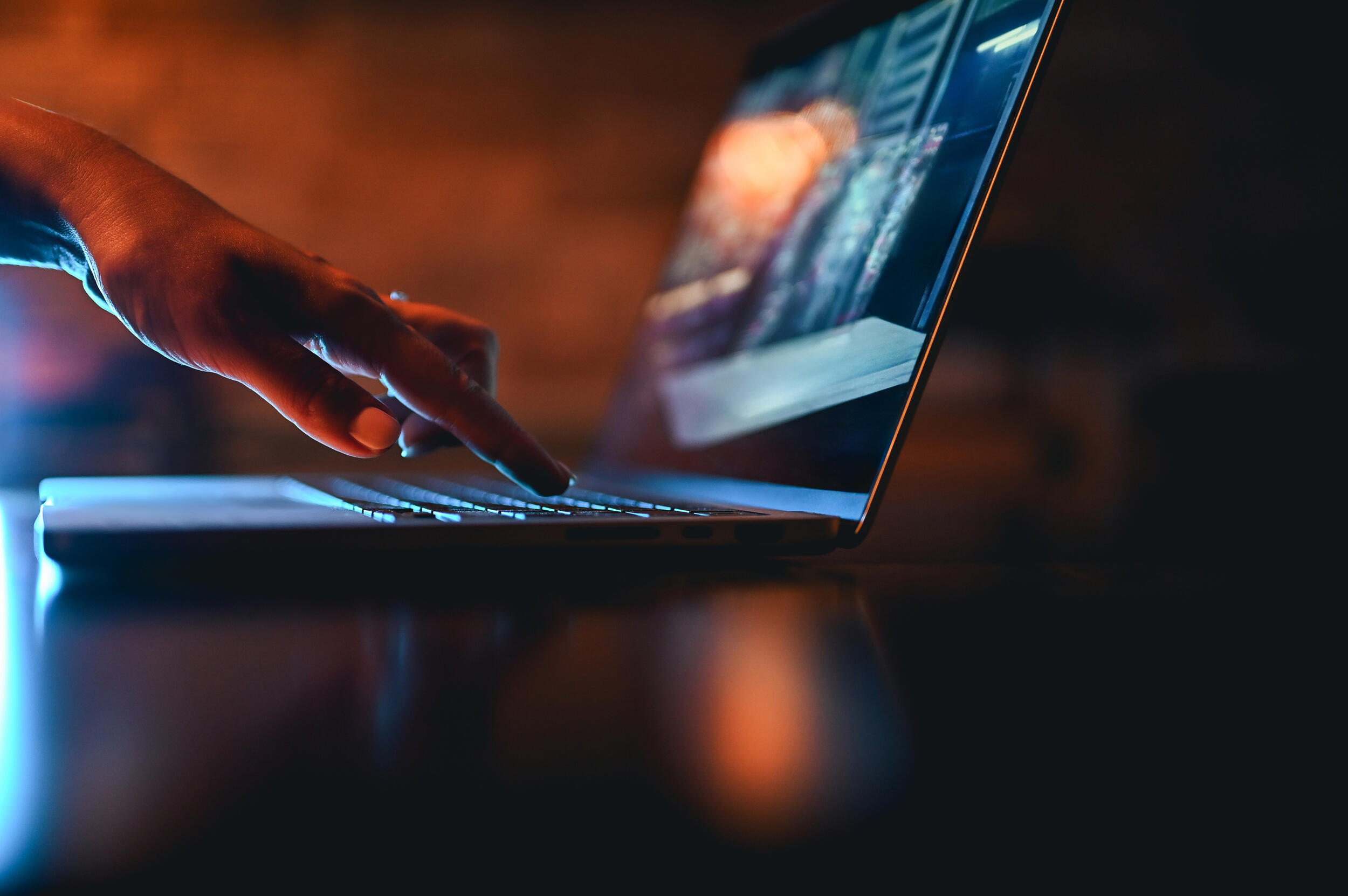 A photo of a hand pressing one key on a laptop. 