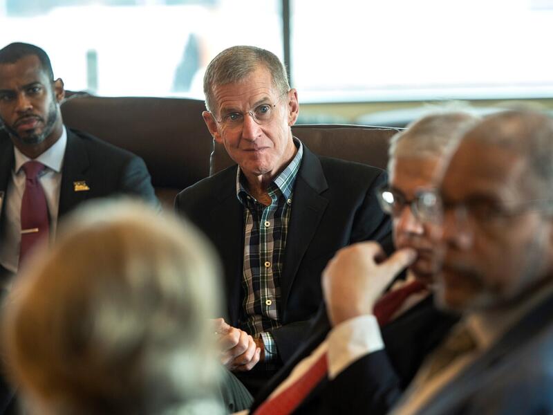 Five people sitting in a semi-circle. The first three people in the front are blurry. 