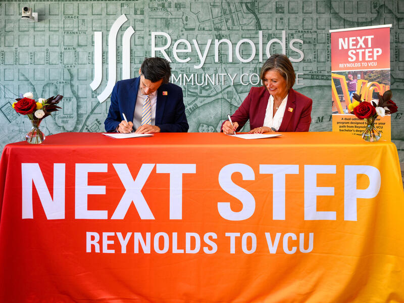 A photo of a man and woman sitting at a table signing documents. 
