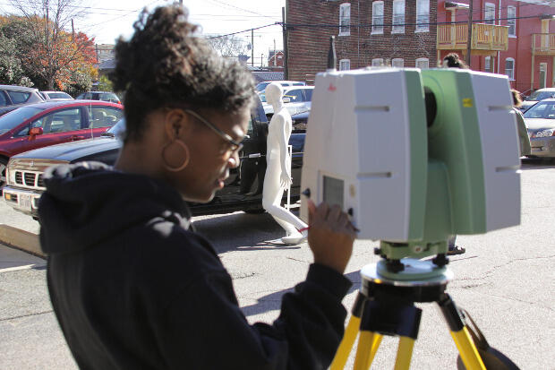 Forensic science majors set up a 3-D scanner to document a reconstructed murder scene.