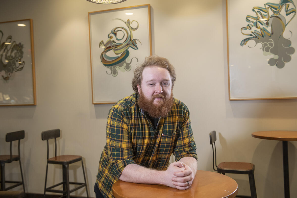 A photo of a man leaning on a table. 