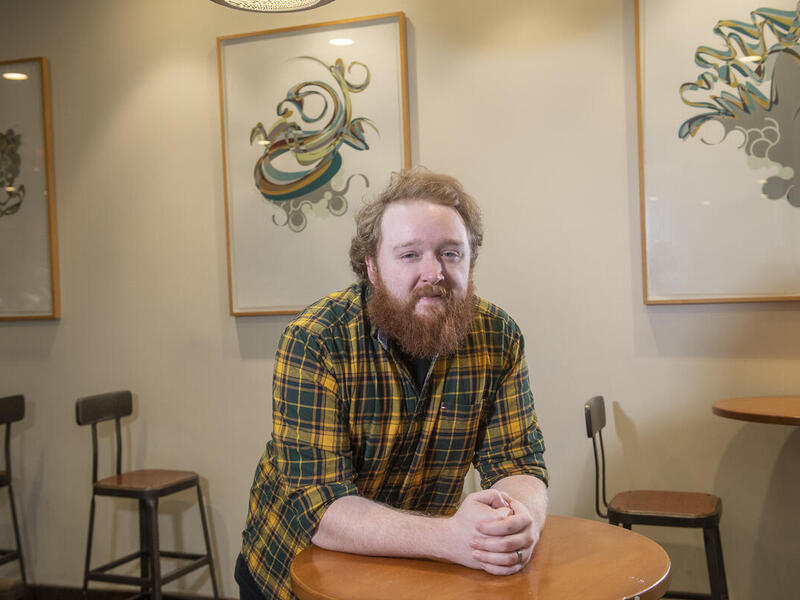 A photo of a man leaning on a table. 