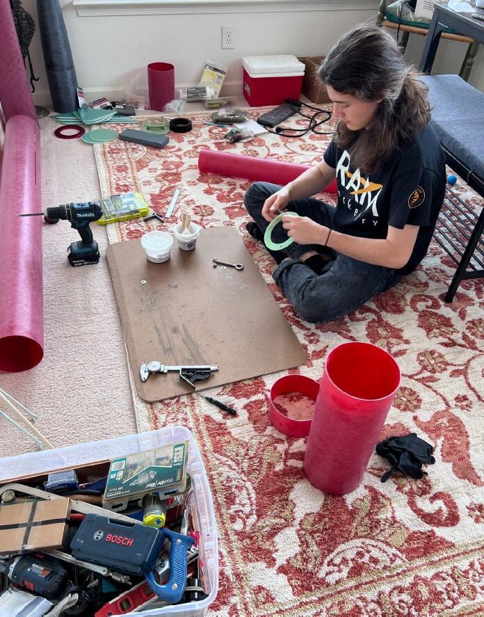 A photo of a person sitting on the floor surrounded by tools 