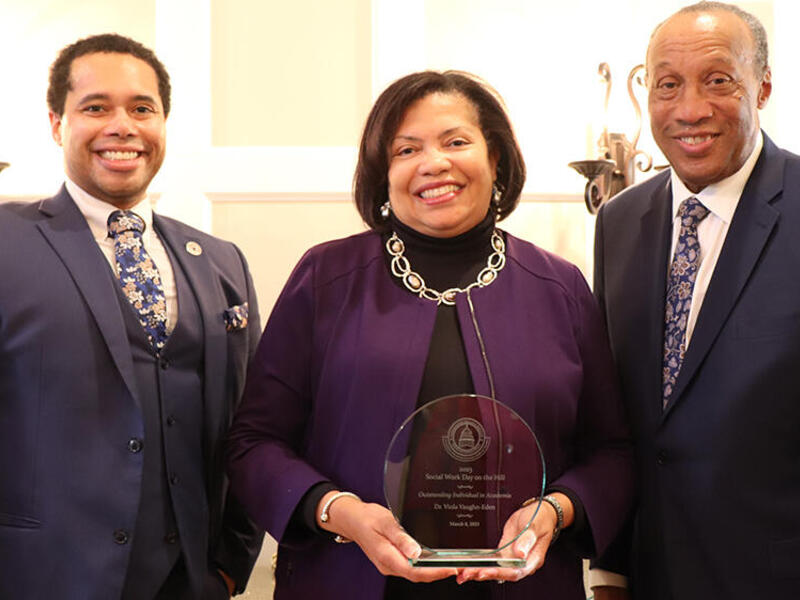 From left to right: Justin Hodge, Viola Vaughan-Eden and Charles Lewis smile for the camera. Vaughan-Eden holds an award. 