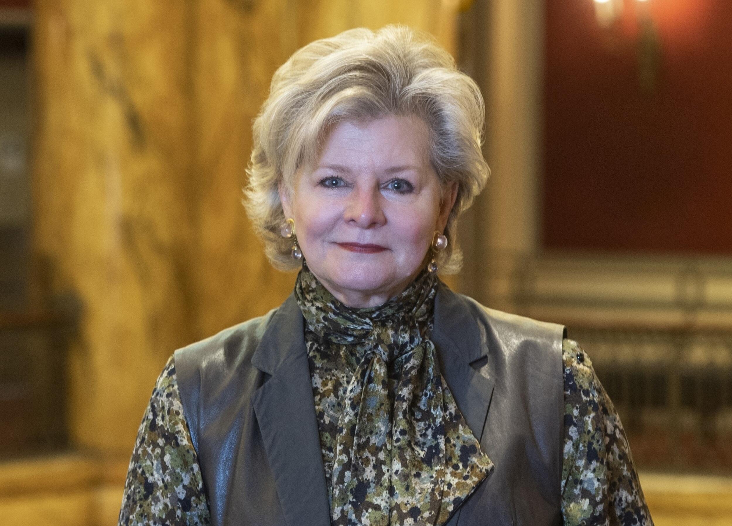 Charlotte Moss standing up with one arm propped on a railing. 