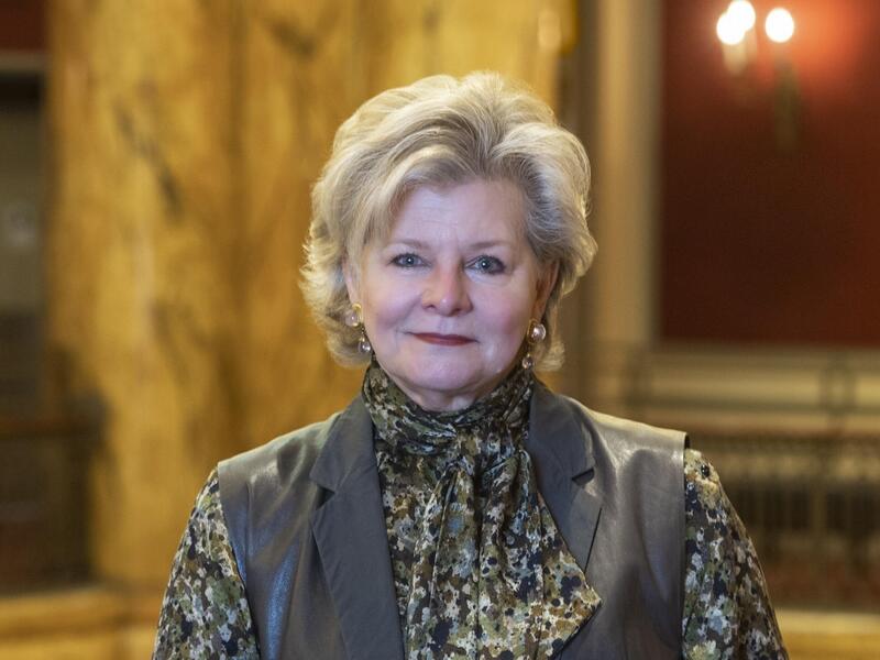 Charlotte Moss standing up with one arm propped on a railing. 