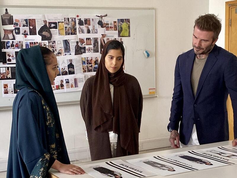 Two women and one man standing at a table with photos on it 