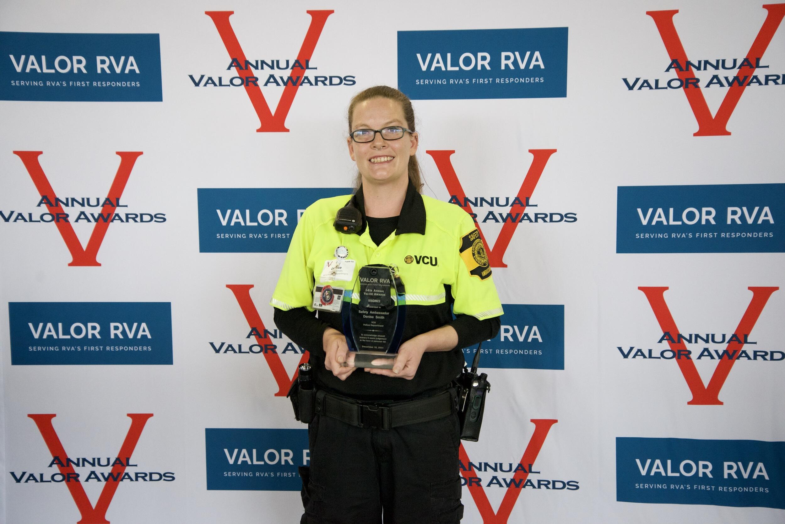 A photo of a woman from the knees up holding a trophy. 