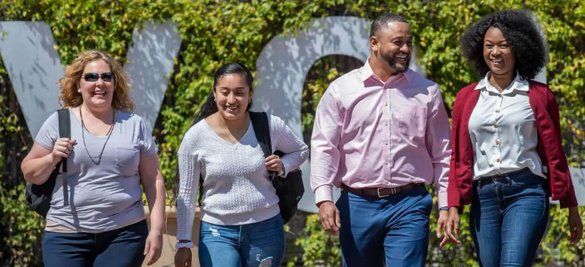 A photo of four people walking away from a sign that says \"VCU\" 
