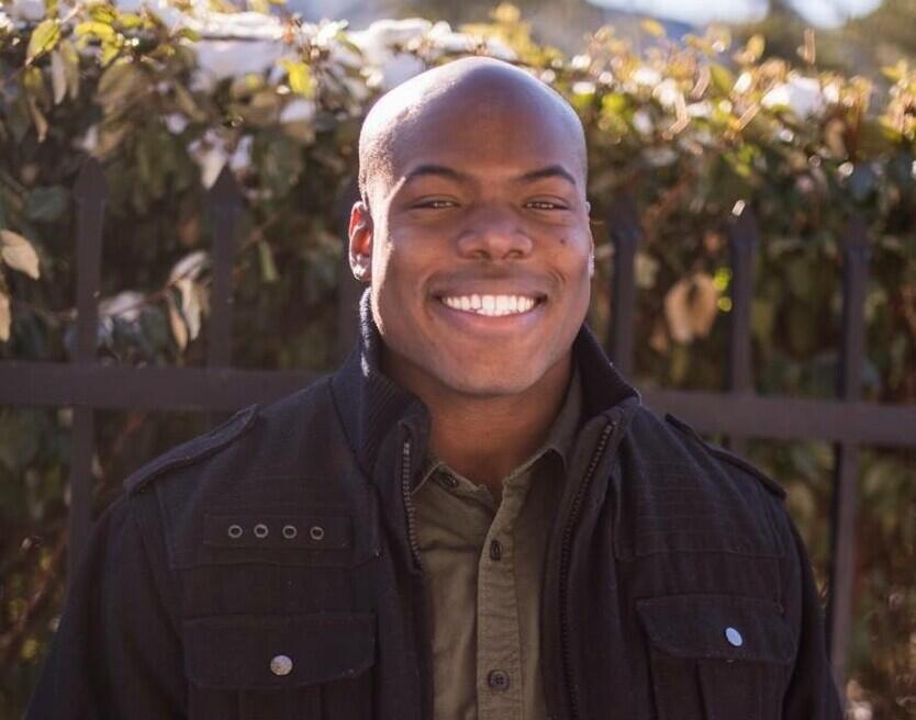 A photo of a man in a black jacket smiling 