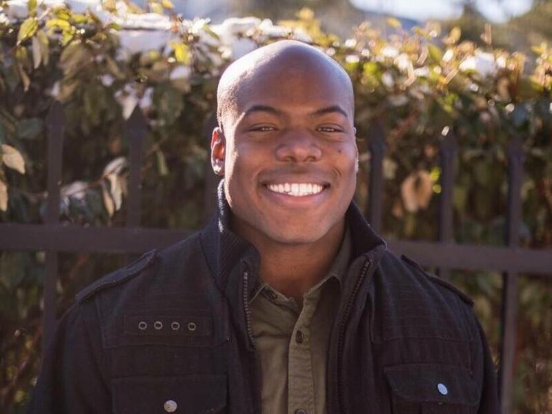 A photo of a man in a black jacket smiling 