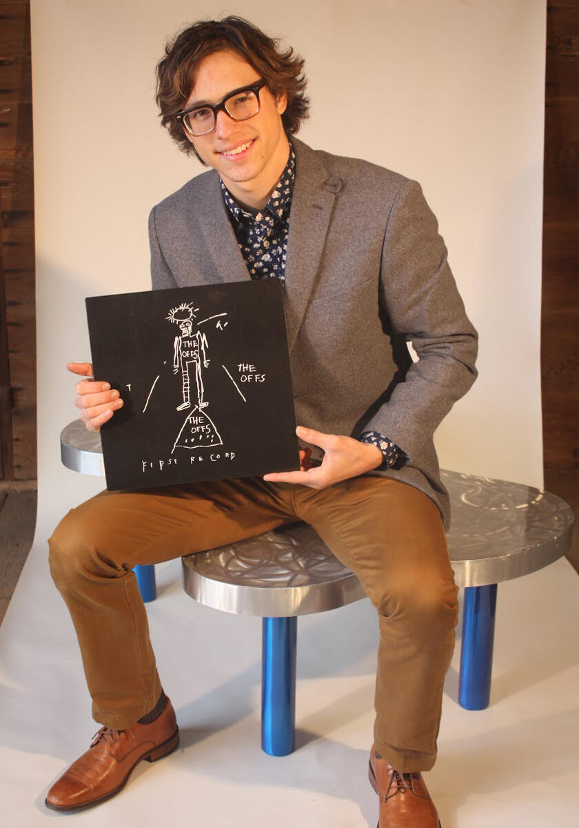 Michael Farmer holding a highly collectible vinyl record and record sleeve of The Offs "First Record," designed and printed by artist Jean-Michel Basquiat in 1981.
